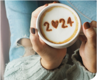 Jemand hält eine Tasse Kaffee mit 2024 drauf 
